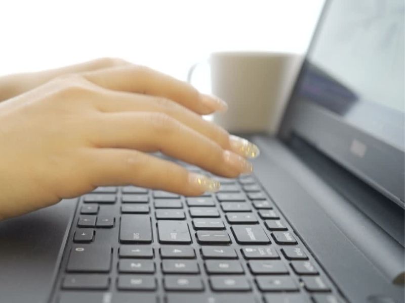 Devojka sa zlatno belim noktima koristi laptop