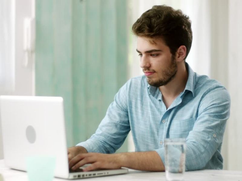 Muškarac u plavoj košulji koristi laptop