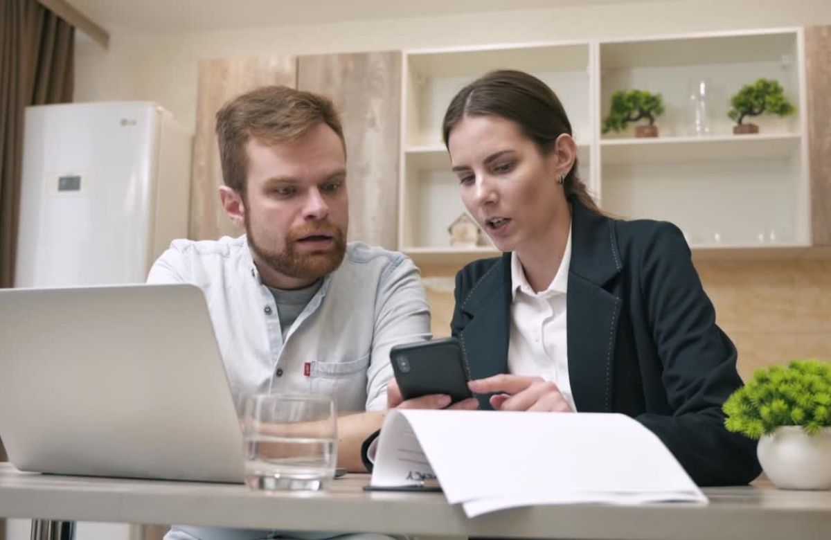 momak i devojka listaju po telefonu i pregledaju papire za kredit
