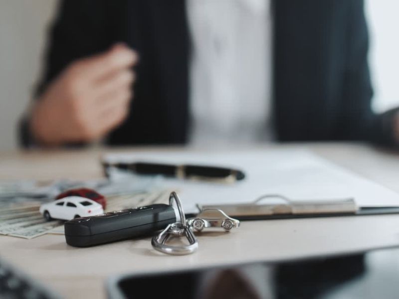Notar overava dokumentaciju o prodaji vozila, na stolu ključevi, ugovor, igračka automobila 