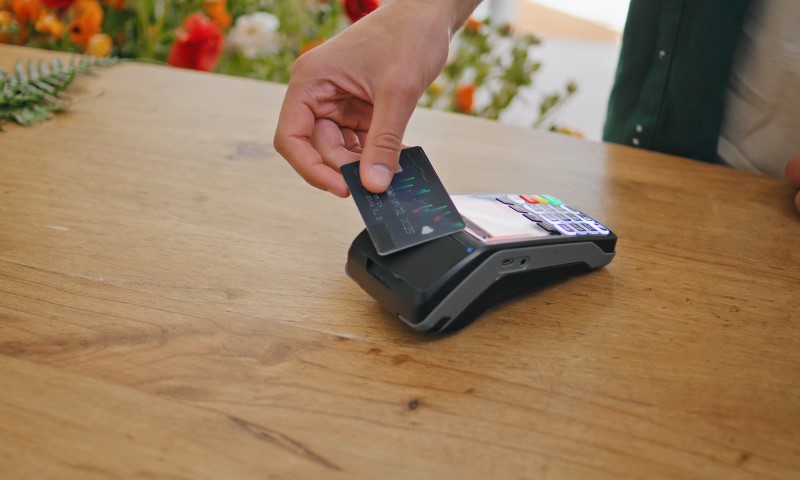 Osoba plaća račun u prodavnici karticom