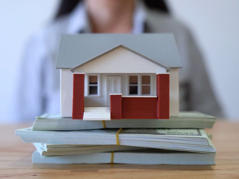 prikaz novca na kom stoji maketa kuće simulirajući na stambeni kredit