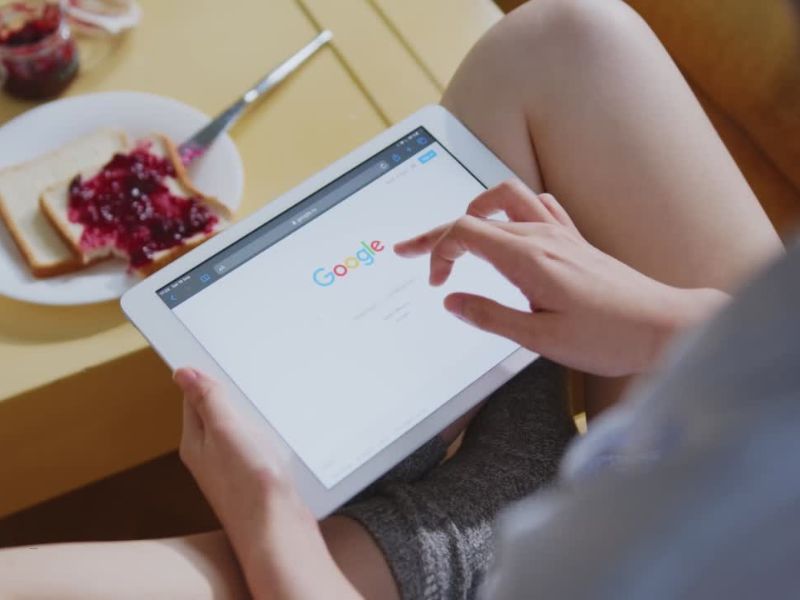 osoba gugla preko tableta i jede tost sendvič sa marmeladom