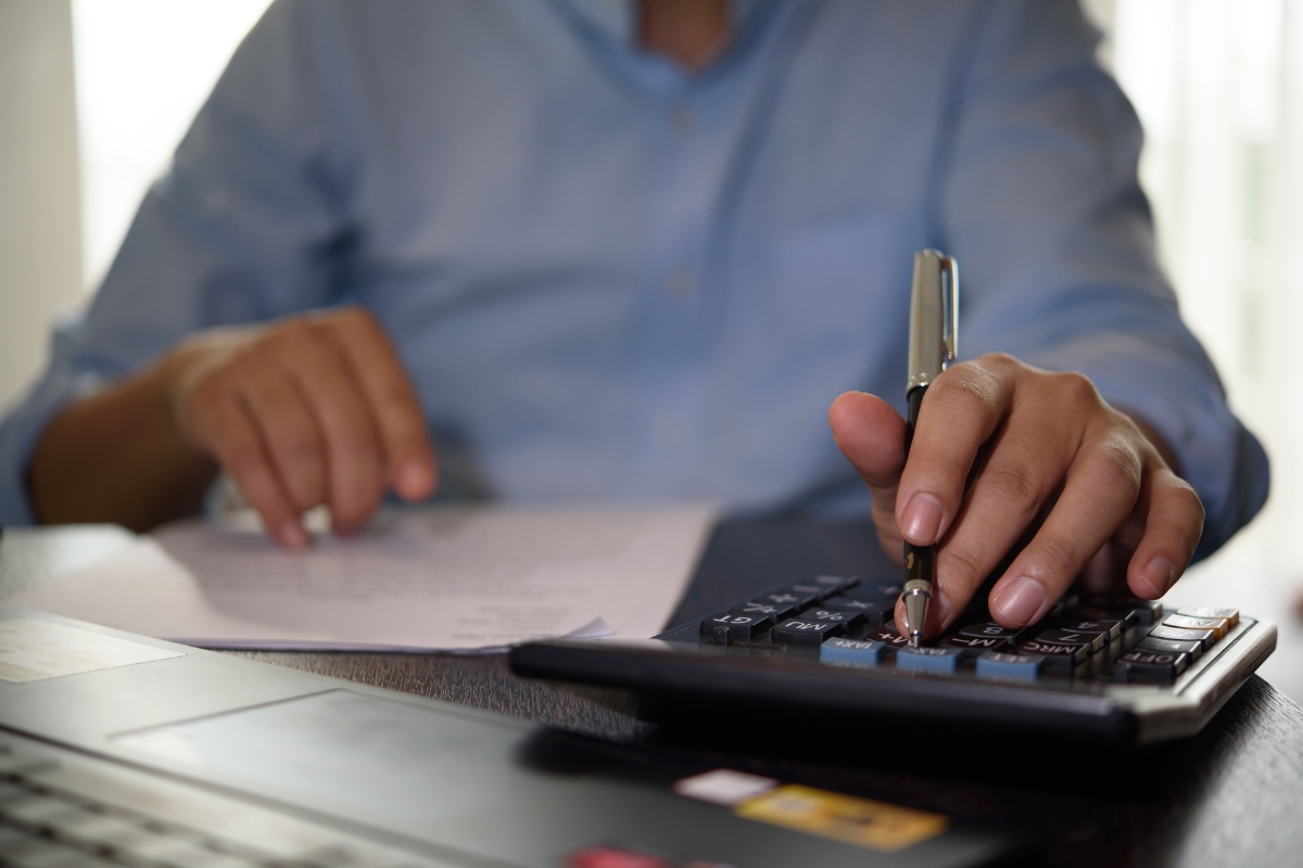 osoba koristi kalkulator i zapisuje nešto na papiru